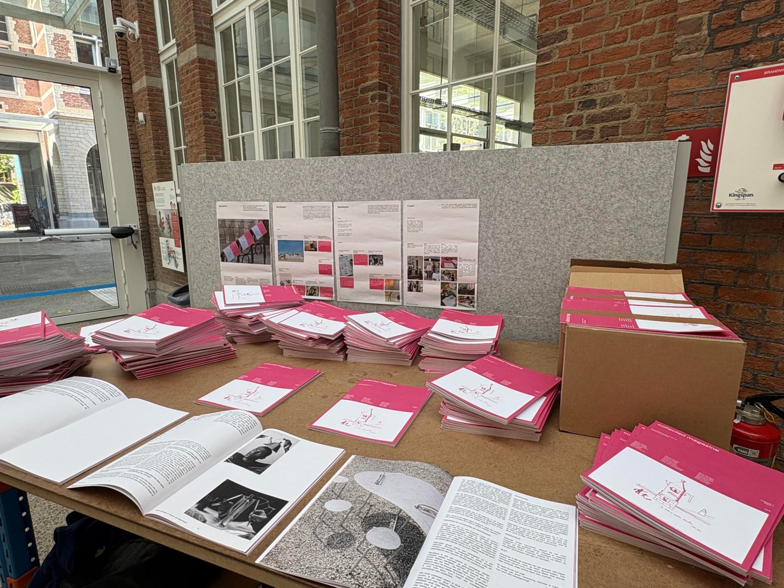 Stacks of magazines on a table with process posters behind them