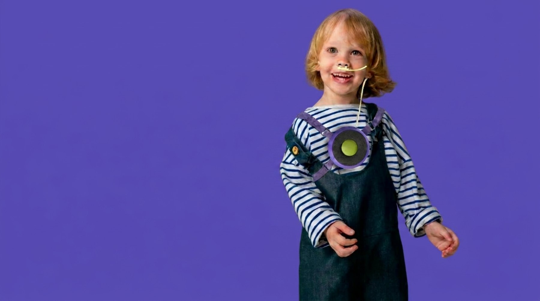 Smiling child wearing Oxi on the chest with purple straps