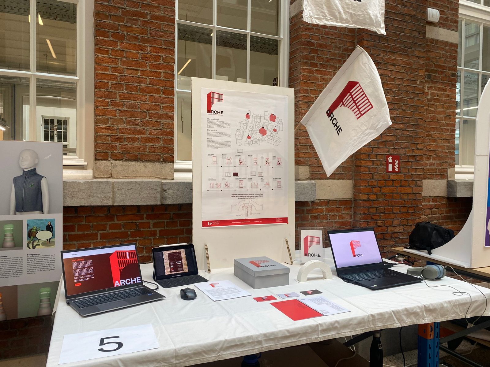 ARCHE exhibition stand with poster, flag, metaphor box and platform on laptops